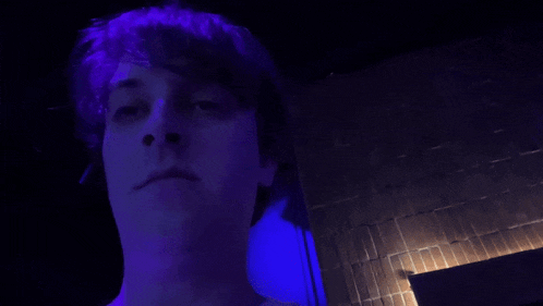 a blurry picture of a man 's face in a dark room with purple lights