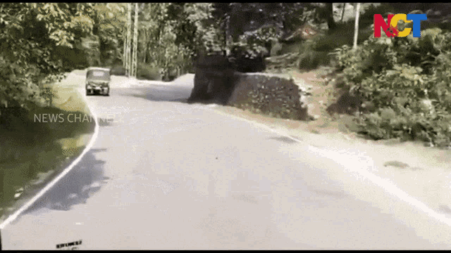 a car is driving down a road with a news channel logo on the bottom