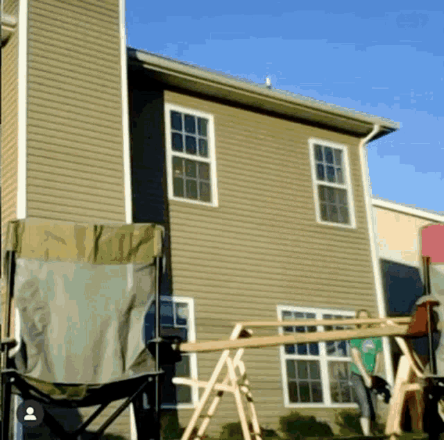 a house with a chair in front of it and a person standing in front of a swing set