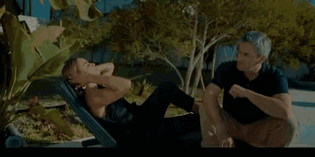 a man and a woman are sitting on a couch on a patio .