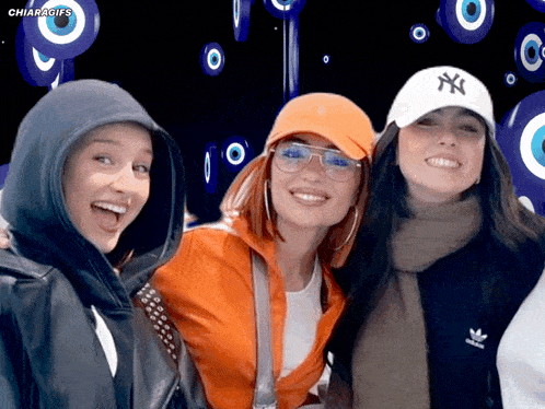 three women are posing for a picture and one of them is wearing a ny hat