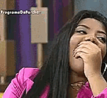 a woman is covering her mouth with her hand while wearing a pink jacket .