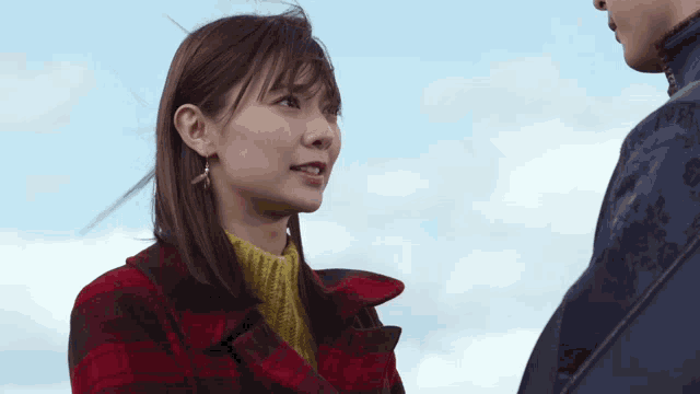 a woman in a plaid coat is talking to a man in a blue jacket