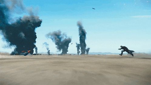 a man is flying through the air in front of a large explosion in the desert