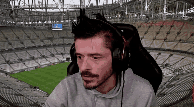 a man wearing headphones sits in front of a stadium