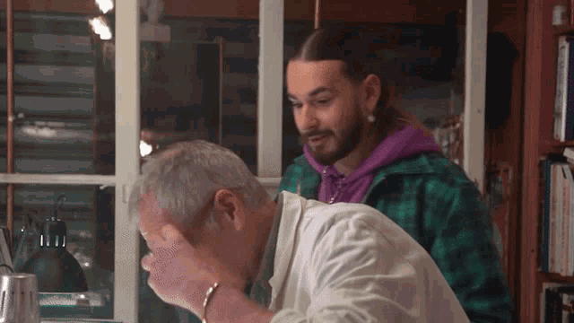 a man in a purple hoodie stands next to another man in a white coat