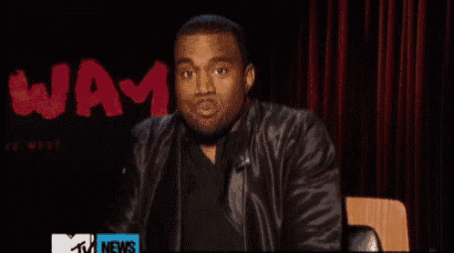 a man in a leather jacket is sitting in front of a red curtain with the word waam written on it .