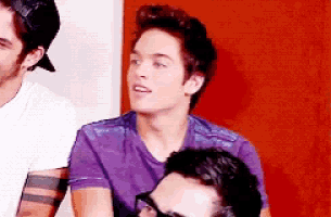 a young man in a purple shirt is sitting next to another young man
