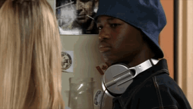 a man wearing headphones and a hat looks at a woman