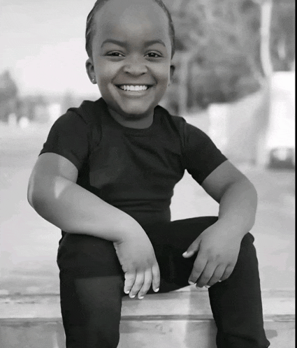 a little boy in a black shirt is smiling for the camera