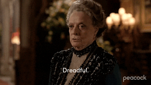 a woman in a black dress is saying dreadful in a room .
