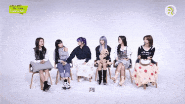 a girl with purple hair holds a stuffed dog and points at another girl