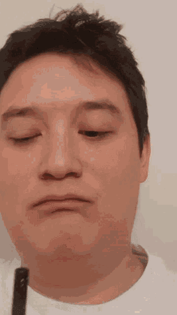 a close up of a man making a face with his eyes closed