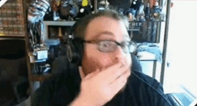 a man wearing headphones and glasses covering his mouth