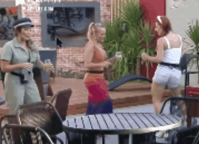 a group of women are standing around a table and chairs .