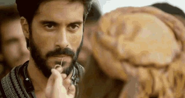 a man with a beard is being touched by a woman with a needle .
