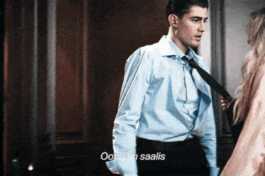 a man in a blue shirt and tie is talking to a woman