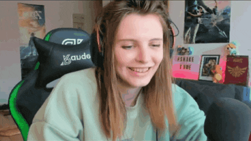 a girl wearing headphones and a kaudo pillow smiles