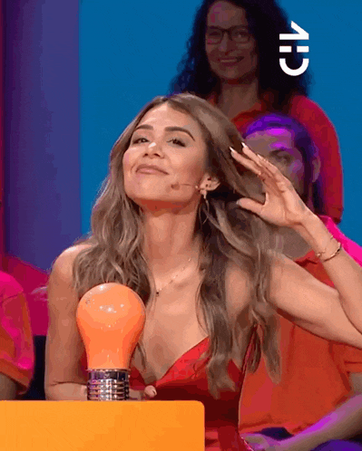 a woman in a red dress holds an orange light bulb in front of her