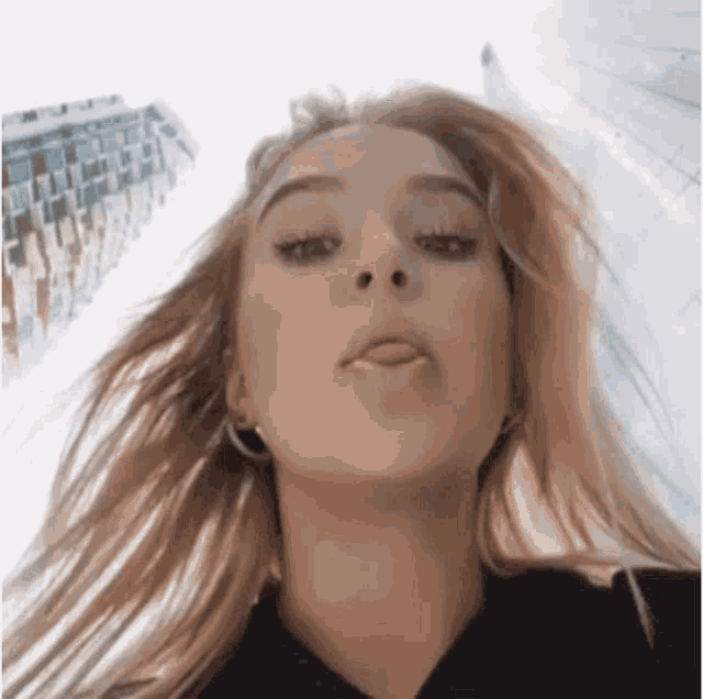 a close up of a woman 's face with her tongue out and her hair blowing in the wind .