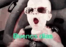 a baby wearing sunglasses is driving a car and yawning .