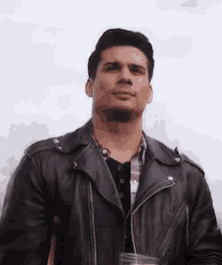a man wearing a black leather jacket is holding a glass of water .