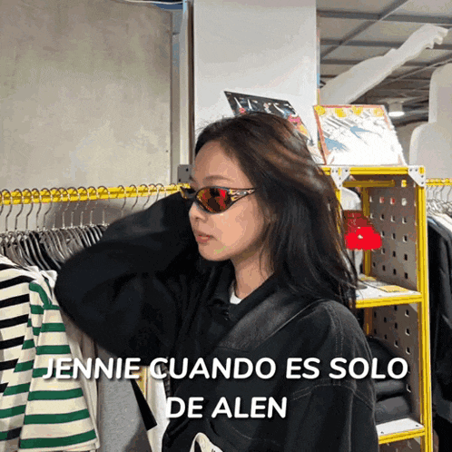 a woman wearing sunglasses is standing in front of a rack of clothes with the words jennie cuando es solo de alen below her