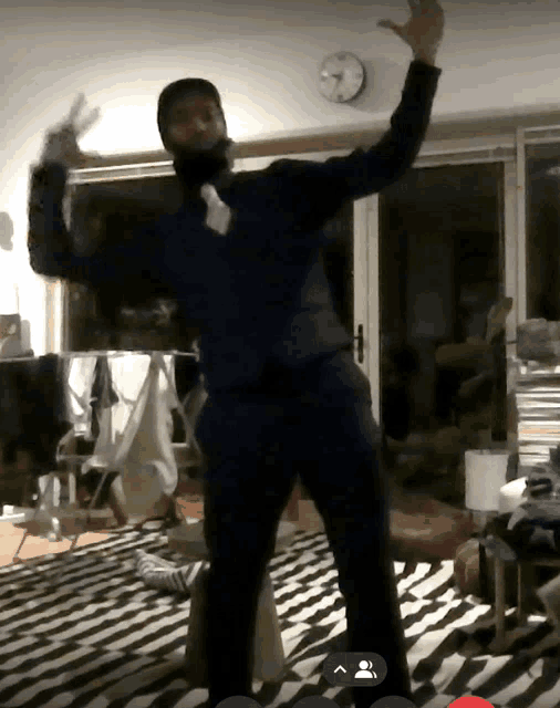 a man in a suit and tie is dancing in front of a clock on the wall