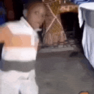 a blurry picture of a man in a striped shirt standing in front of a table .