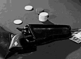 a black and white photo of a gun on a table with coins .