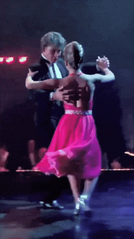 a man in a tuxedo is dancing with a woman in a red dress