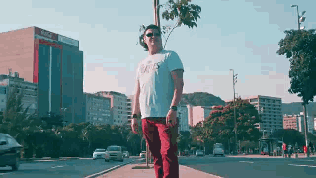 a man is standing on a sidewalk in front of a building that says coca cola on it .