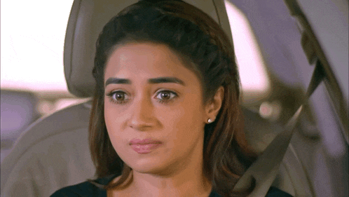 a woman is sitting in the back seat of a car and making a funny face .