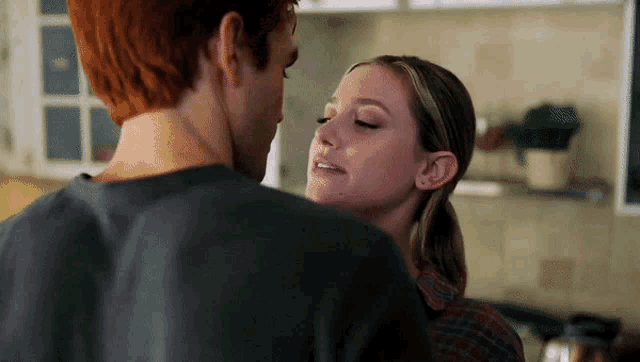 a man and a woman are standing next to each other in a kitchen and kissing .