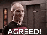 a bald man is standing in front of a door with the words `` agreed '' written on it .