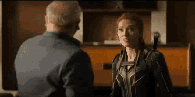 a woman in a black suit is talking to a man in a room .