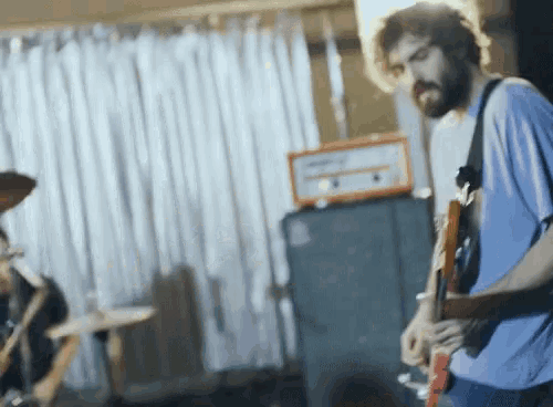 a man playing a guitar in front of an orange amplifier