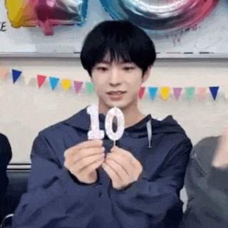 a young man is holding a birthday candle with the number ten on it .
