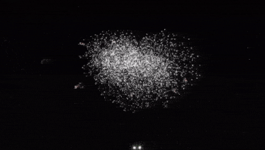 a black and white photo of a fireworks display at night