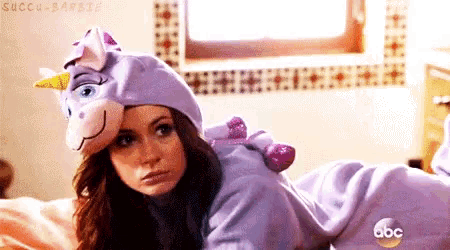 a woman in a unicorn costume is laying on a bed