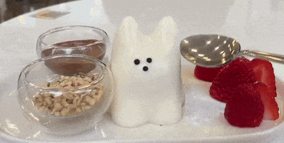 a white bunny shaped dessert with strawberries and chocolate sauce on a plate