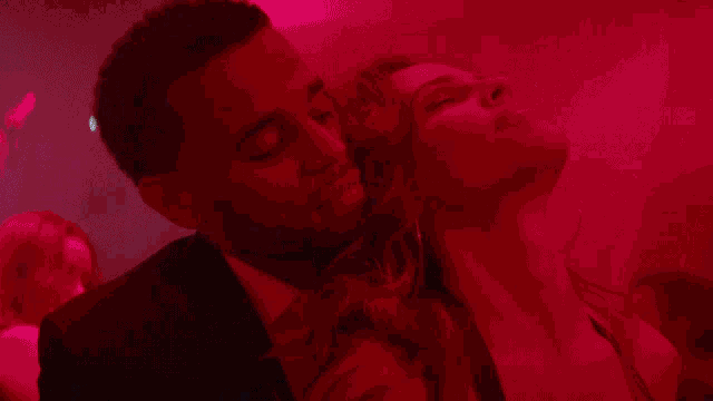 a man and a woman are kissing in a dark room in front of a crowd .