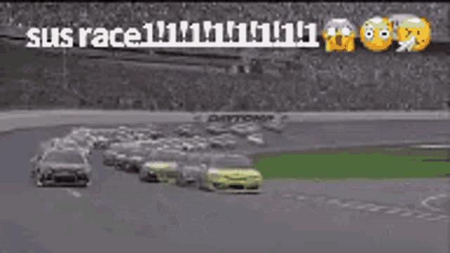 a group of cars are racing on a race track with a crowd watching .