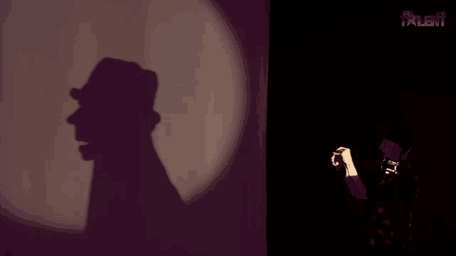 a shadow of a man in a hat is projected on a wall next to a poster for the talent