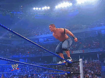 a wrestler is jumping over the ropes in front of a crowd with a sign that says march