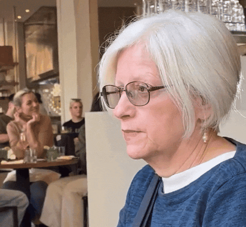 a woman wearing glasses and a blue shirt is sitting in a restaurant