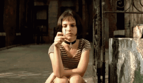 a woman with a choker around her neck is sitting on the sidewalk
