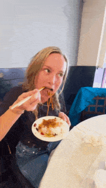 a woman eating noodles with chopsticks from a plate
