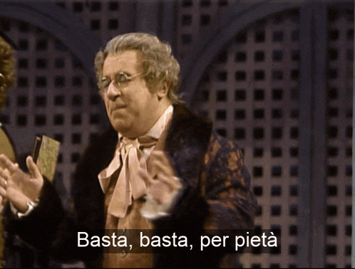 a man in a fur coat stands next to another man with the words basta basta per pieta above him