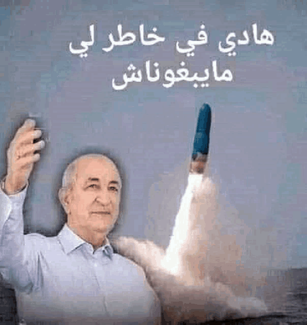 a man is holding a rocket in his hand with arabic writing on it